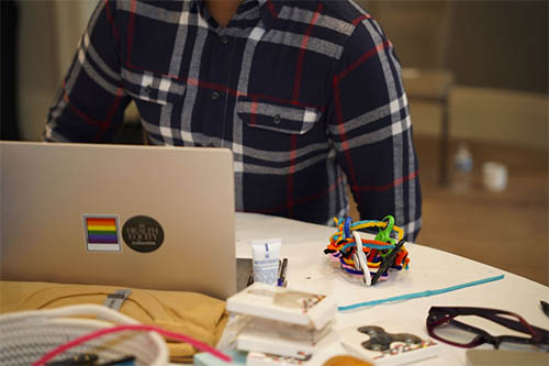 person sitting behind a laptop with a rainbow sticker